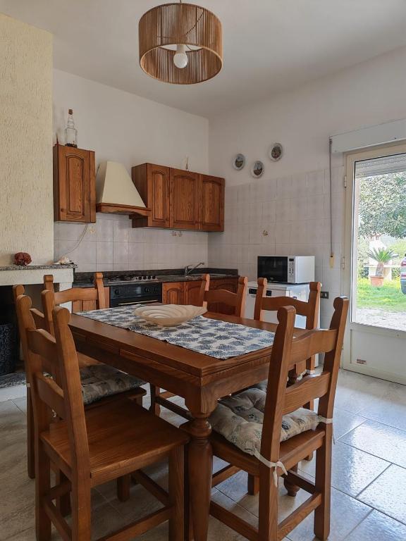 a kitchen with a wooden table with chairs and a kitchen at Su Muscadeddu in Tertenìa