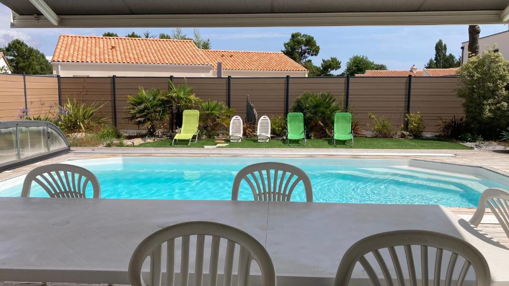 a table and chairs next to a swimming pool at Villa turquoise - piscine privée, terrasse bois in Saint-Jean-de-Monts