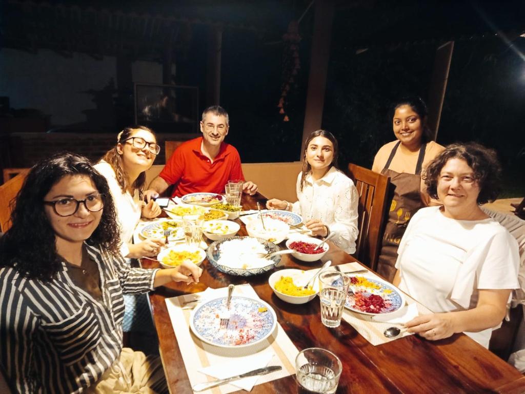 a group of people sitting around a table eating food at Monkey Jungle Cottage in Udawalawe