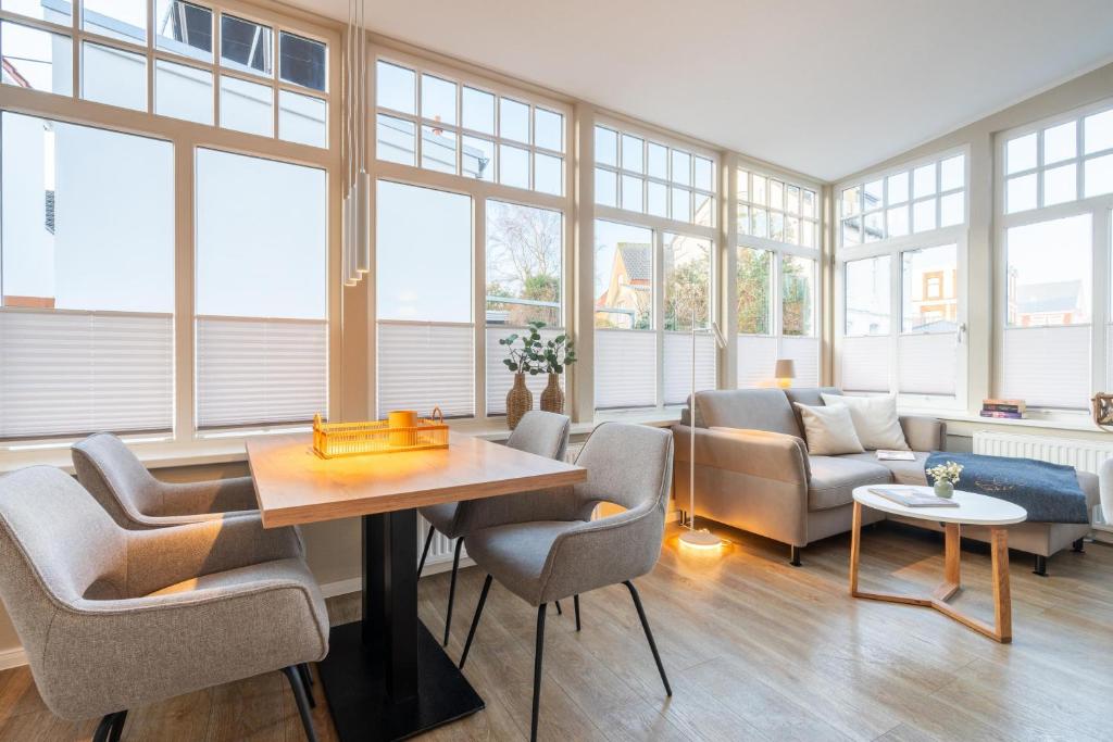 a living room with a table and chairs and windows at Woge2 Appartement 1 in Borkum