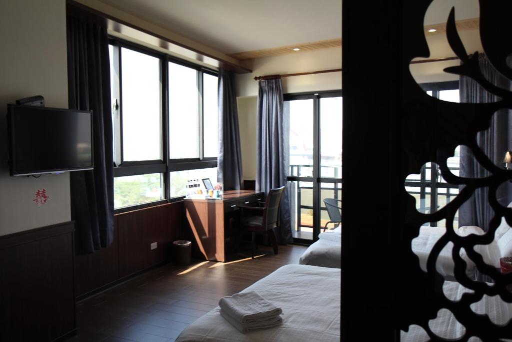 a hotel room with a bed and a desk and window at Lu Fang View in Donggang