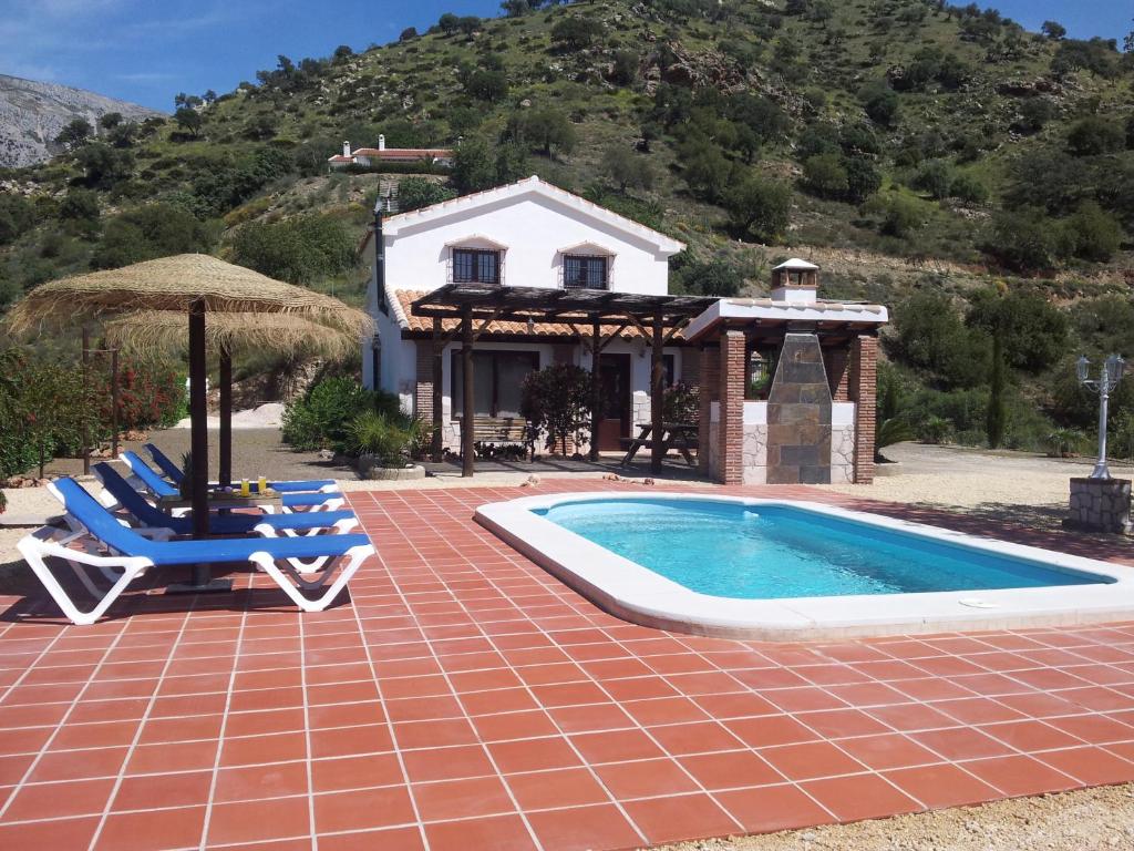 a house with a swimming pool and two chairs at Casita la Herilla in El Chorro