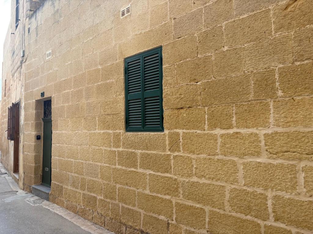 a brick wall with a green window on a building at Guesthouse 39 in Mqabba