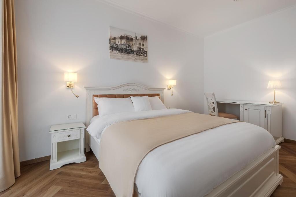 ein weißes Schlafzimmer mit einem großen weißen Bett und zwei Lampen in der Unterkunft Casa Doseanu in Oradea
