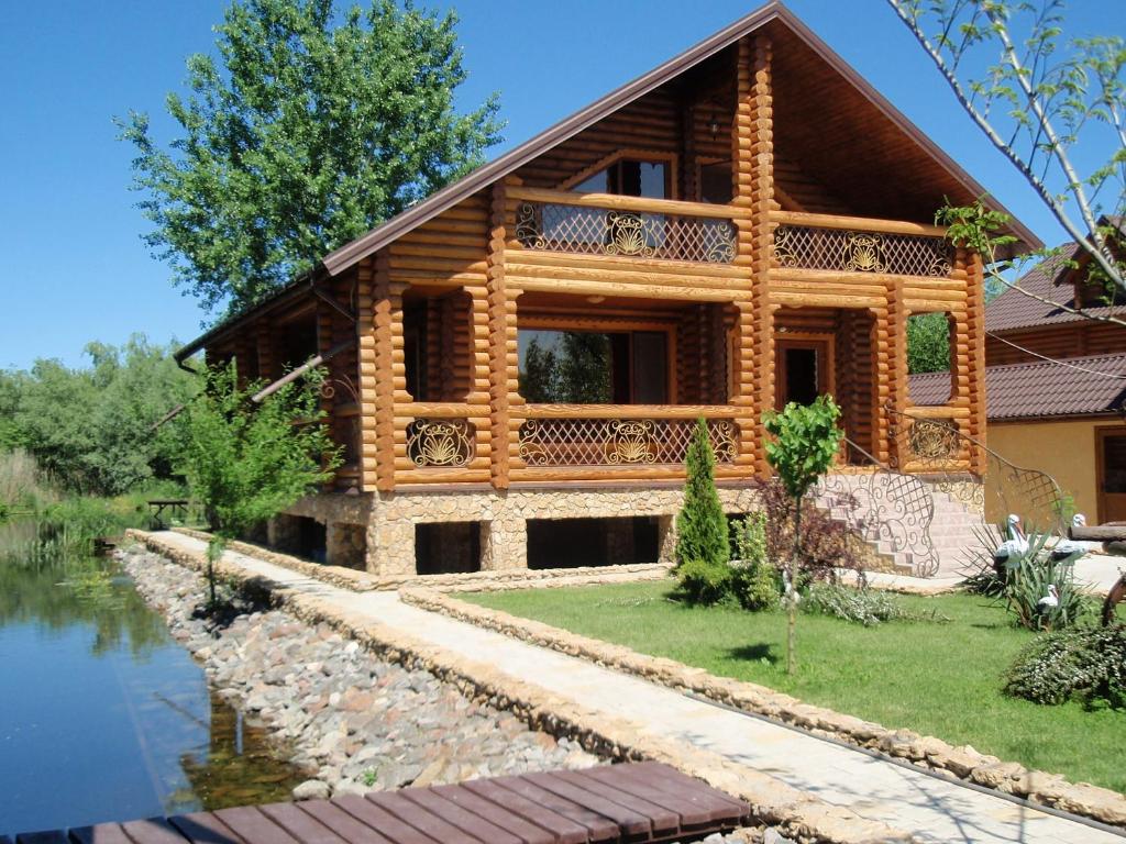 a log house with a river in front of it at Tihaya Gavan in Vylkove