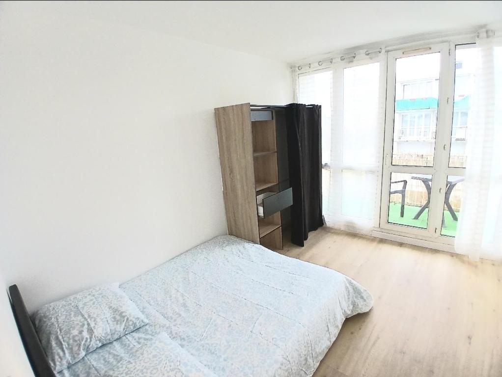 a white bedroom with a bed and a window at Eves Rooms in Saint-Michel-sur-Orge