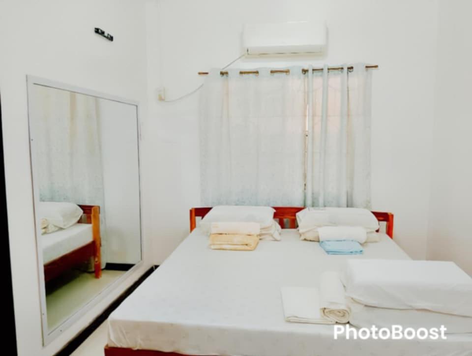 a bedroom with a white bed and a mirror at Zoldyck 2 Home in Pahanocoy