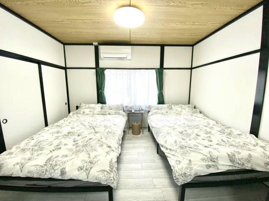 two beds in a small room with a window at comodo inn HANAZONO in Aomori