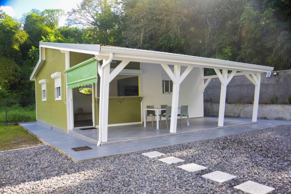 a small yellow house with a porch and a deck at La kaz a sonel, gîte au vert in Morne-à-lʼEau