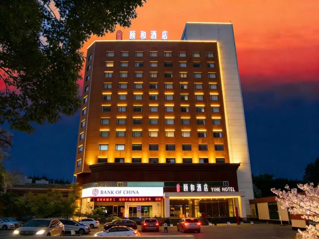 a building with cars parked in a parking lot at Yihe Hotel Luoyang in Luoyang