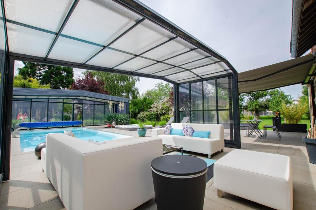a patio with a pool and a glass extension at La Villa Séquoia in Les Bordes-Aumont