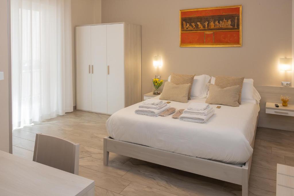 a bedroom with a large white bed with towels on it at B&B Domus Vettii in Pompei