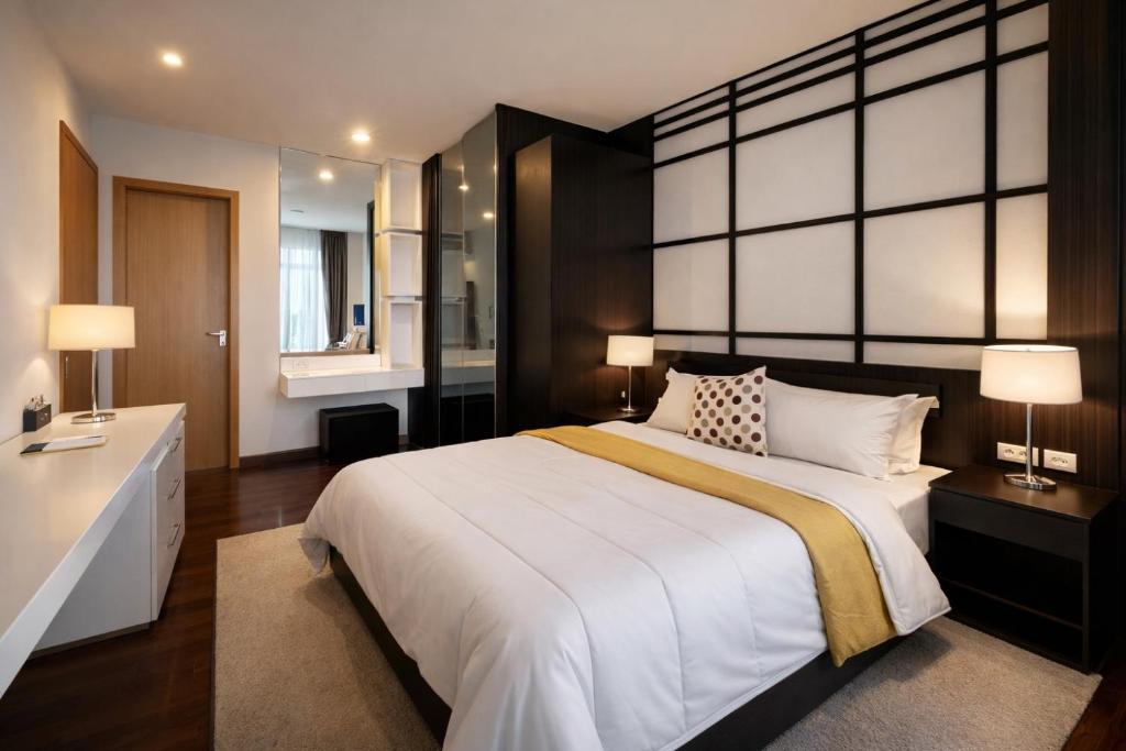 a bedroom with a large bed and a desk and two lamps at NexStay Bangkok Appartment in Bangkok