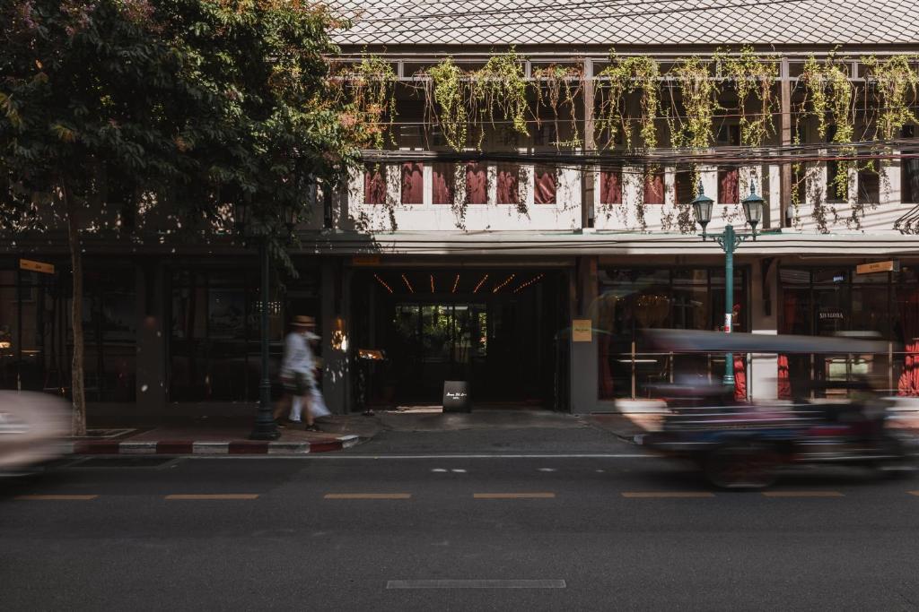 a person riding a skateboard down a street in front of a building at Baan Tuk Din Hotel in Bangkok
