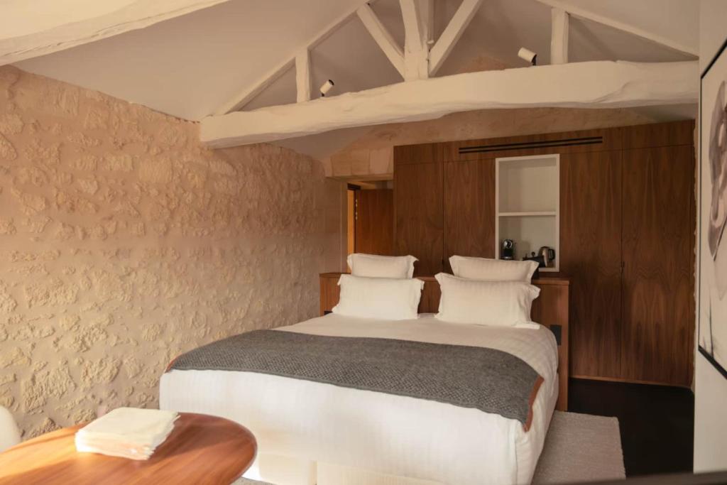 a bedroom with a large bed and a table at Château Fonroque La Suite in Saint-Émilion