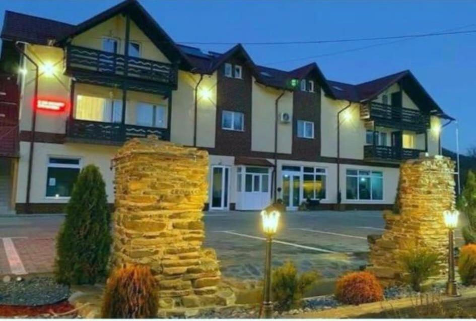 a hotel with a stone wall in front of a building at Paunasul Codrilor in Câmpulung Moldovenesc