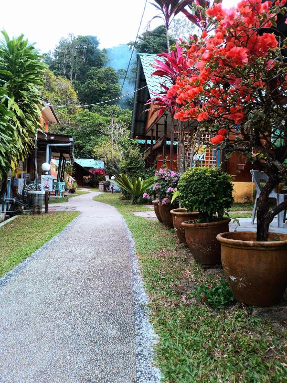 a walkway with large pots of flowers and plants at Cheers Garden Chalet in Kampung Tekek