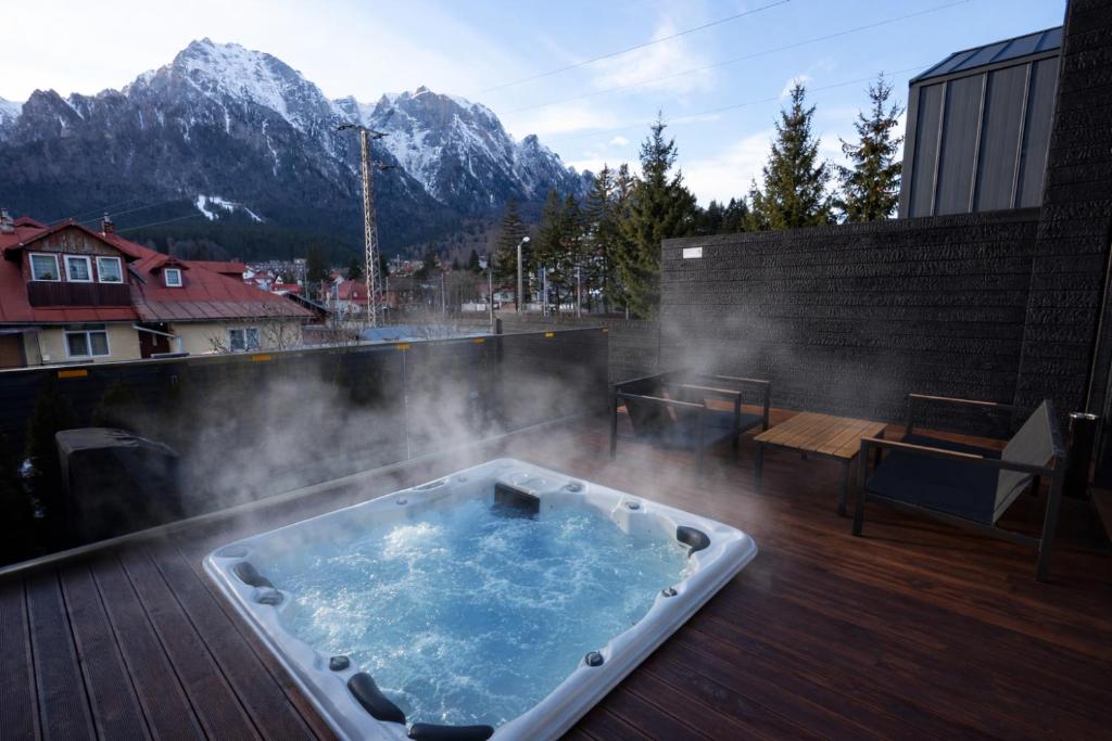 Ein Whirlpool auf einer Terrasse mit Bergen im Hintergrund in der Unterkunft Sky Nest Chalets in Buşteni
