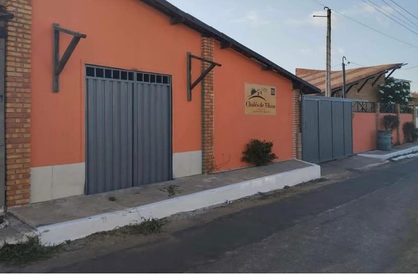 an orange building with a gate on the side of a street at Chalés de Tibau in Tibau