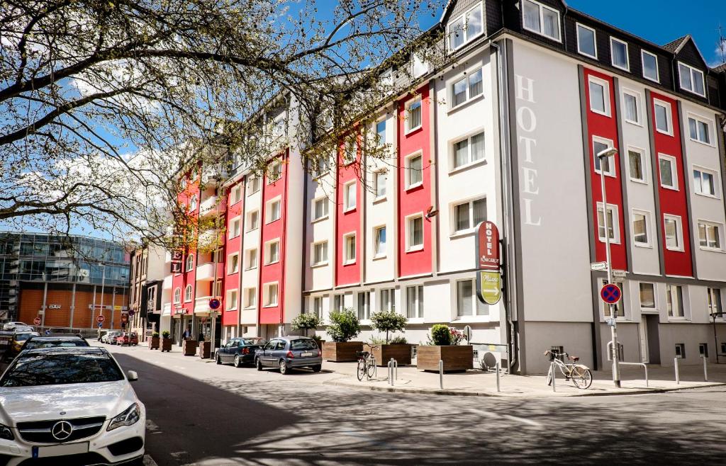 une rangée de bâtiments dans une rue avec des voitures garées dans l'établissement Hotel Königshof am Funkturm, à Hanovre