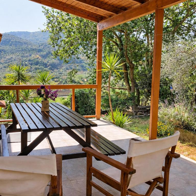 a wooden table and chairs on a patio with a view at Sunshine Home - Peaceful Garden Escape & Parking in Selianitika