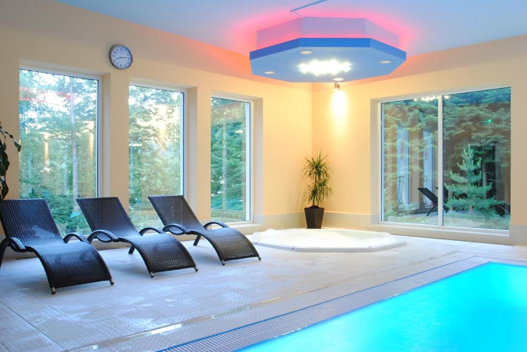 Pokój z basenem, krzesłami i zegarem w obiekcie Pensjonat Szajna Spa w Rymanowie-Zdroju