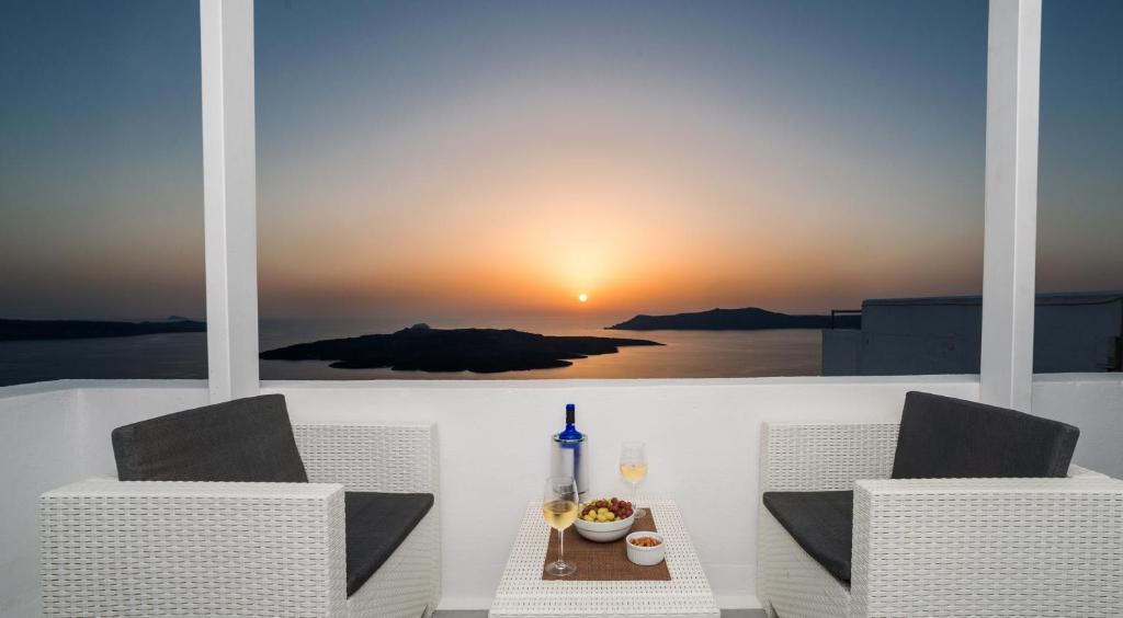 a table and chairs with a view of a sunset at Corrado Caldera Apartments in Fira