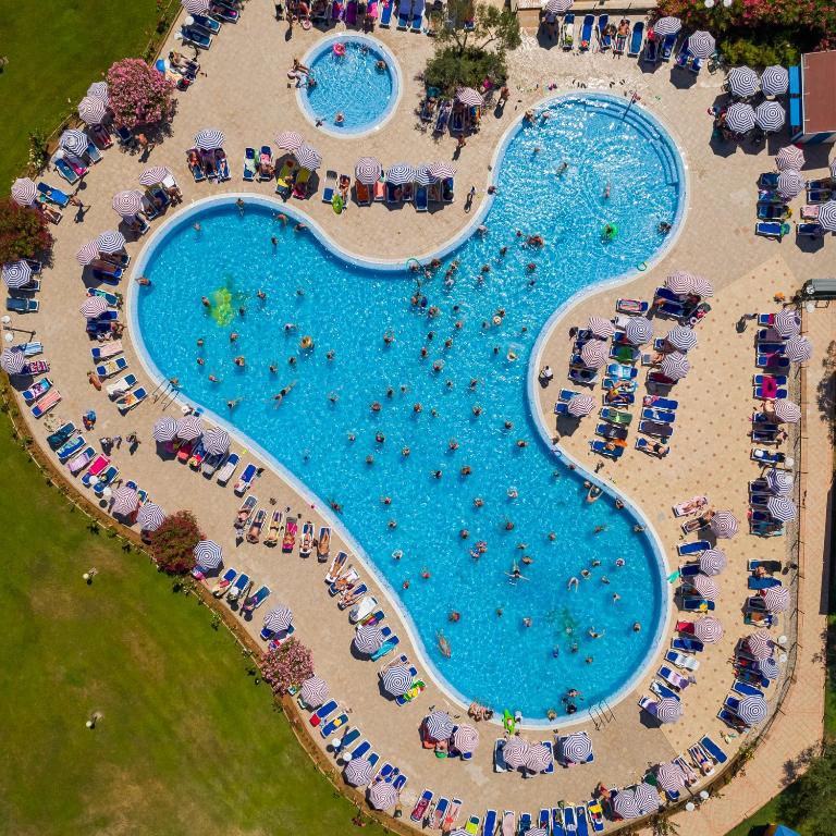an overhead view of a large swimming pool with umbrellas at MASLINICA Oliva Camping Pitches in Rabac