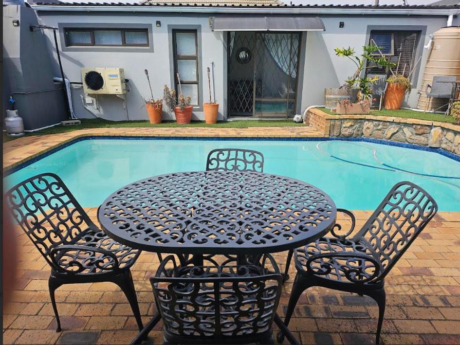 a table and chairs next to a swimming pool at Memoirs in Cape Town in Zeekoevlei