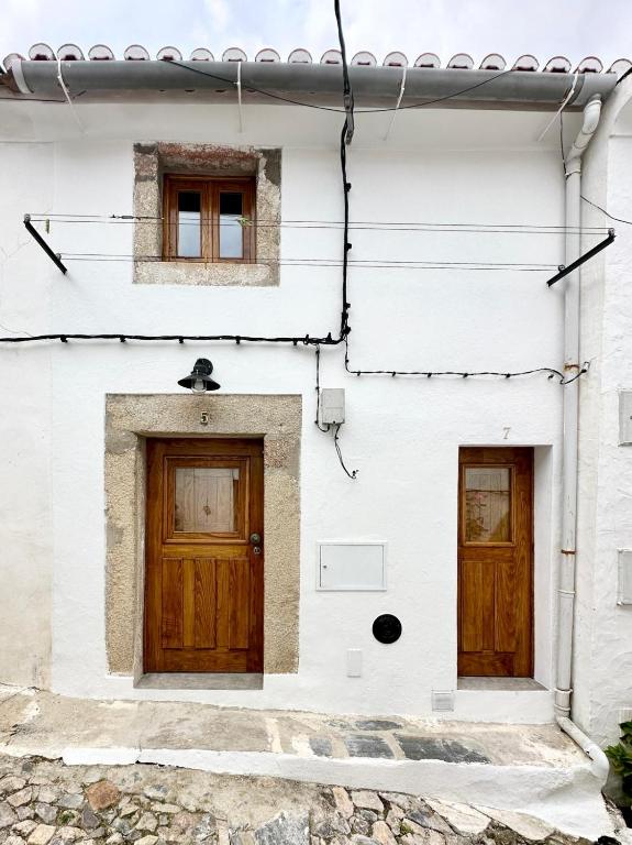 a white house with two wooden doors at Casa do Alva in Castelo de Vide