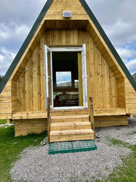 a wooden cabin with a large window and stairs at Sterlochy Cabin in Lochcarron