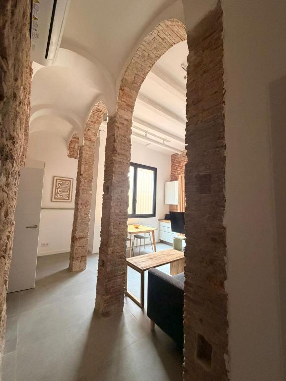 a living room with brick walls and a room with a table at Les Voltes in Palamós