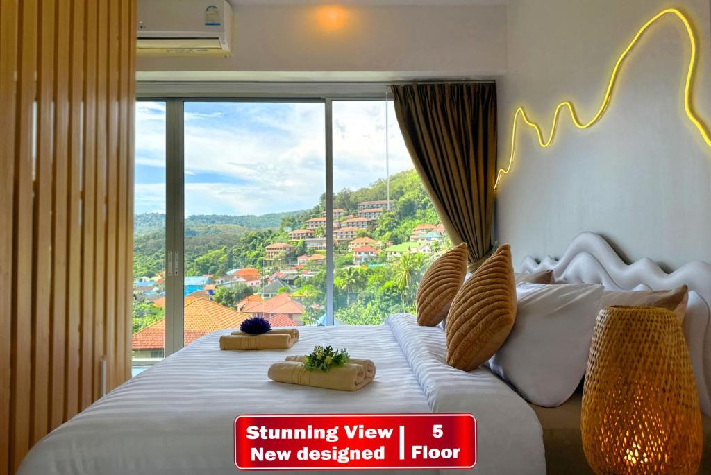 a bedroom with a bed with a large window at Panoramic Condo 50 sqm Karon in Karon Beach