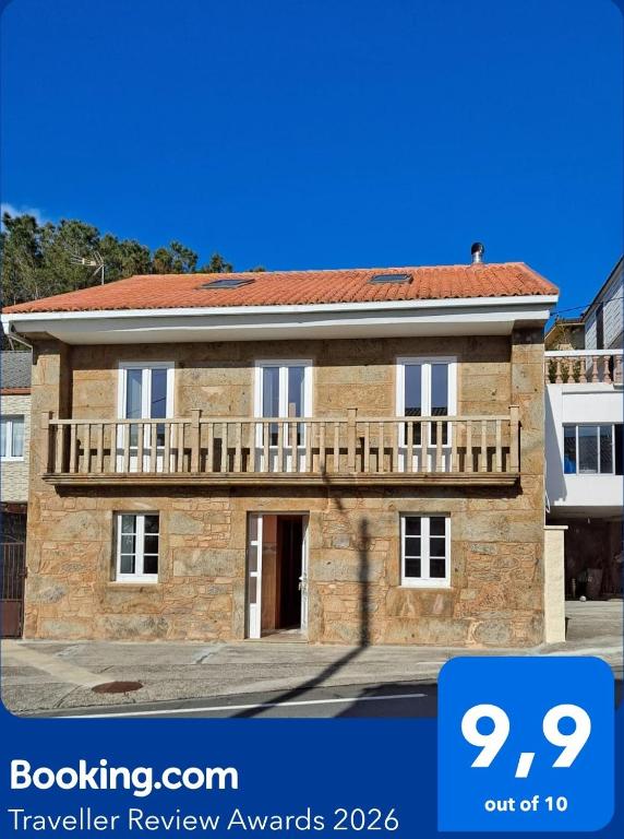 a brick house with a balcony on top of it at Casa Amarela in Corcubión