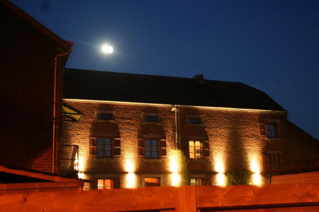 ein großes Backsteingebäude mit Nachtbeleuchtung in der Unterkunft Au Cap in Durbuy
