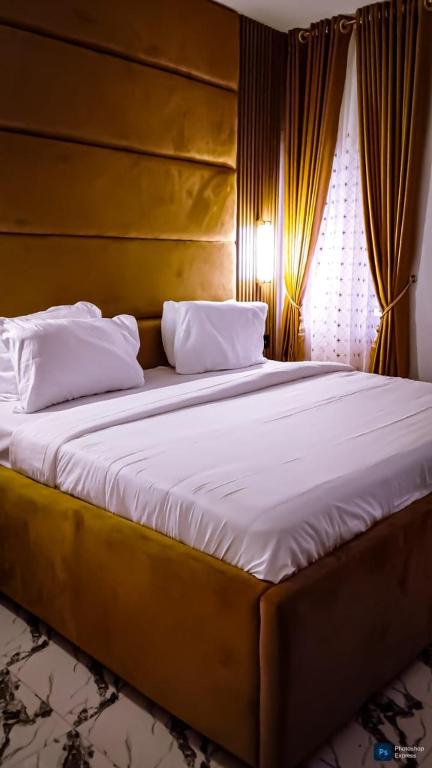 a bedroom with a large bed with a wooden headboard at Enuana Hotel And Suite in Odobor
