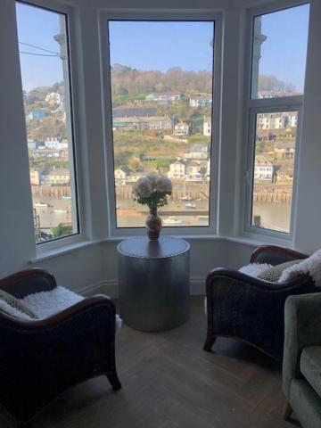 a living room with two chairs and a table and windows at harbourways in Looe