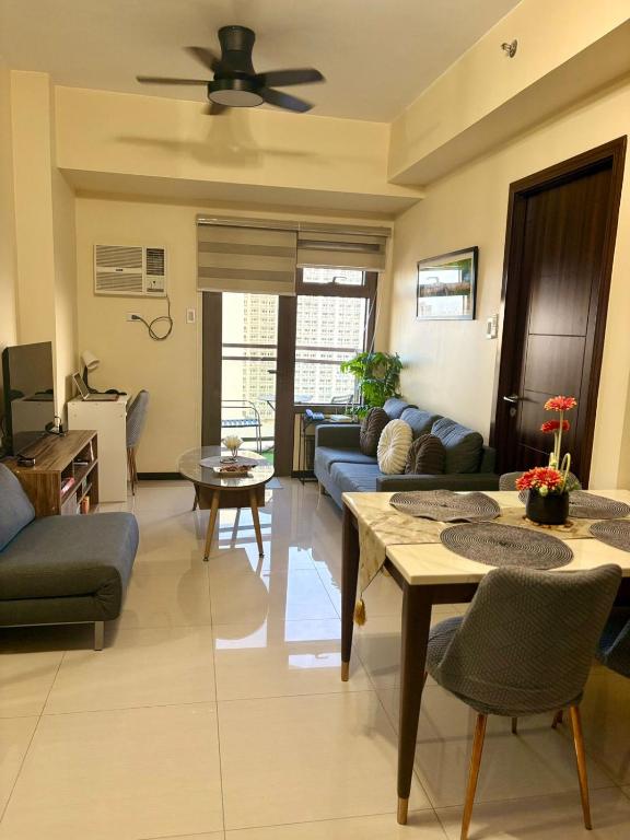 a living room with a couch and a table at Modern Pet Friendly 1br Condo with Balcony near AIRPORT MOA & OKADA Pasay Staycation WFH ready Free Pool Acces Gym and Sauna in Manila