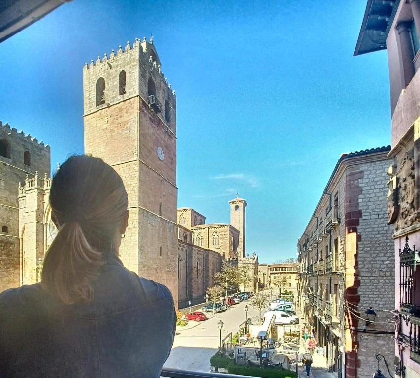 a woman looking out of a window at a clock tower at VUT Casa de la Catedral Alta in Sigüenza