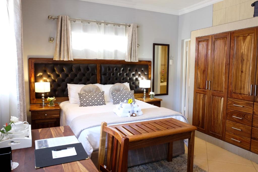 Schlafzimmer mit einem großen Bett mit einem Kopfteil aus Holz in der Unterkunft Firwood Lodge in Pretoria
