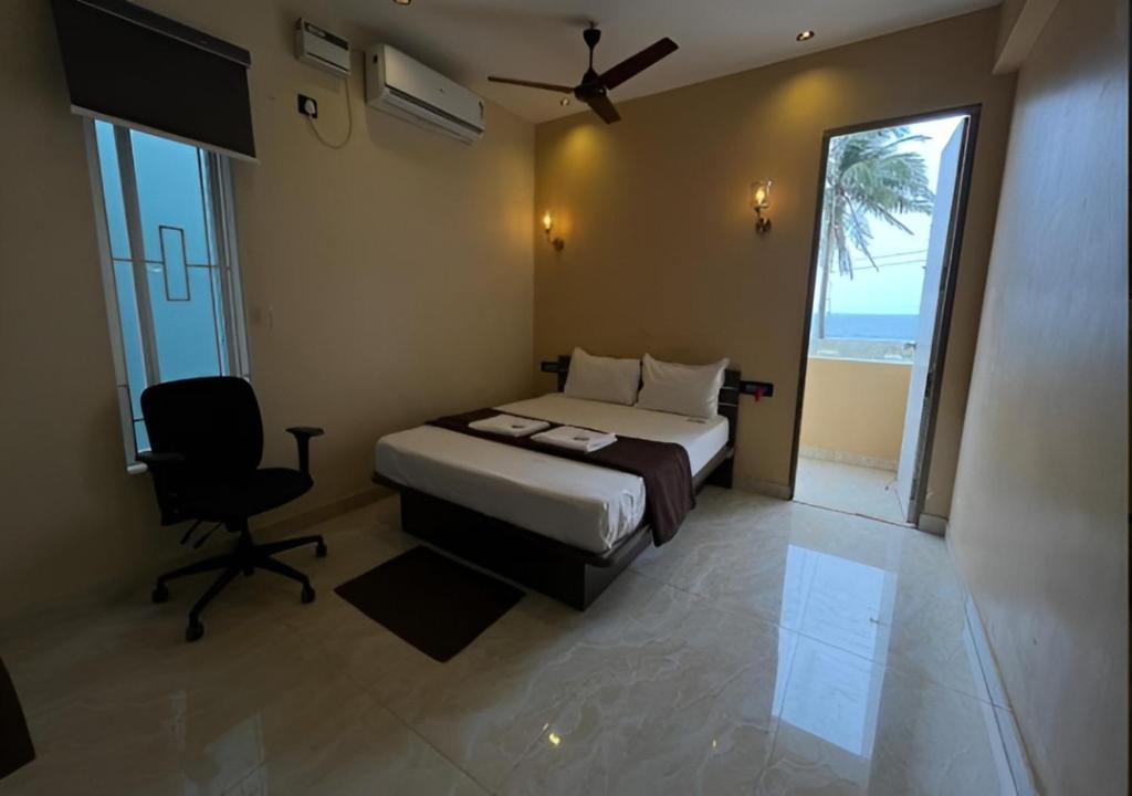 a bedroom with a bed and a chair and a window at The K Inn Wavefront in Mahabalipuram