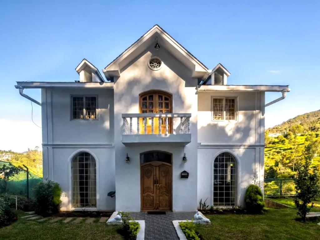 a white house with a door and a balcony at Winterbourne Chalet in Coonoor