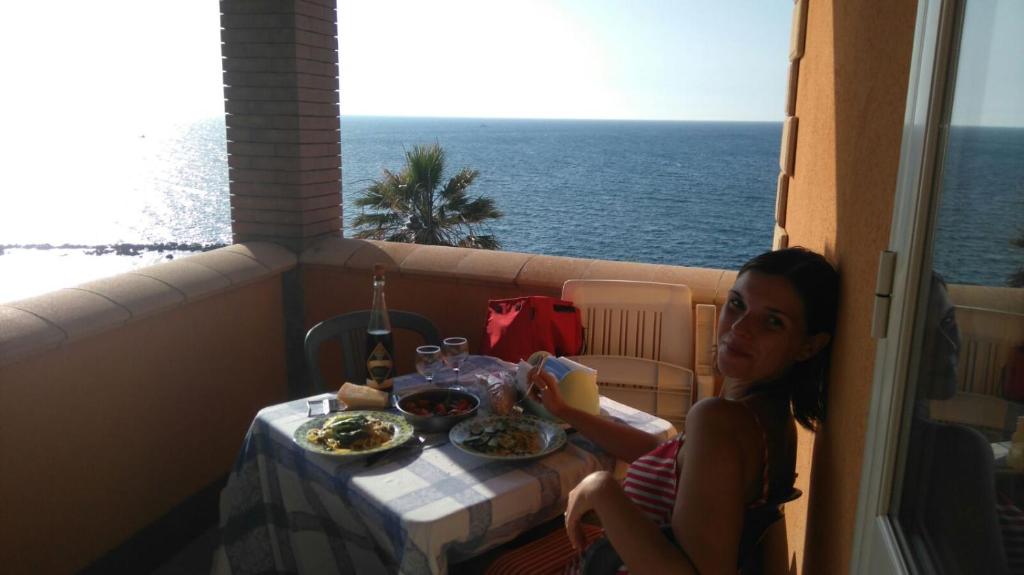 Une jeune femme assise à une table avec une assiette de nourriture dans l'établissement Apartments on promenade, à Trappeto