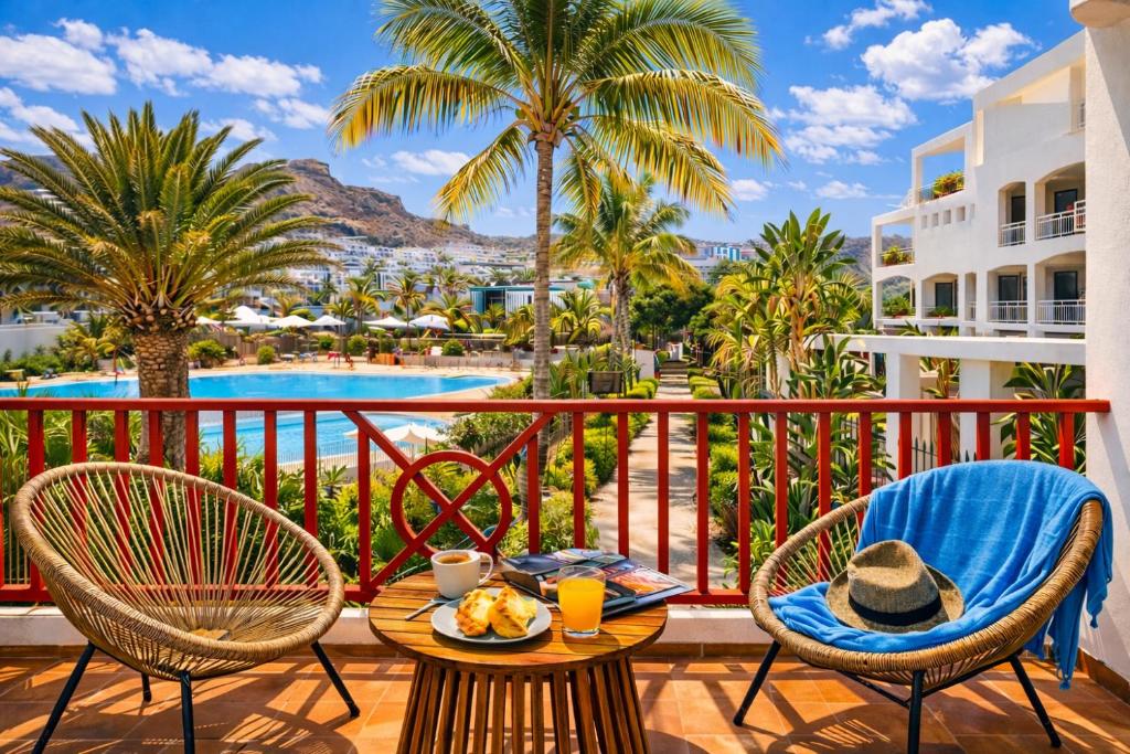 a table and chairs on a balcony with a view of a pool at Sunny Playa del Cura in Playa del Cura