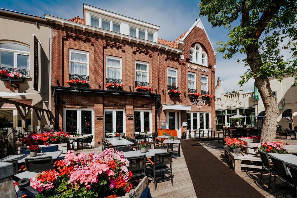 an outdoor patio with tables and flowers in front of a building at Hotel Tholen in Tholen