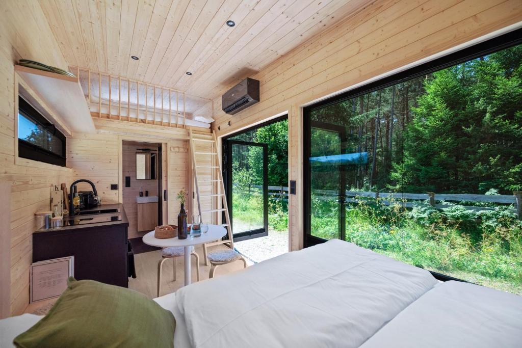 a bedroom in a tiny house with a large window at Tirol Cabin by ALPAMI in Wildermieming