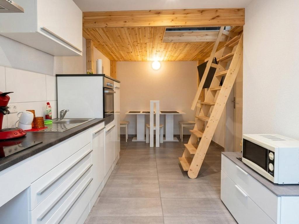 a kitchen with white cabinets and a dining room with a table at Grenz-Apartment an der Aach in Rielasingen-Worblingen