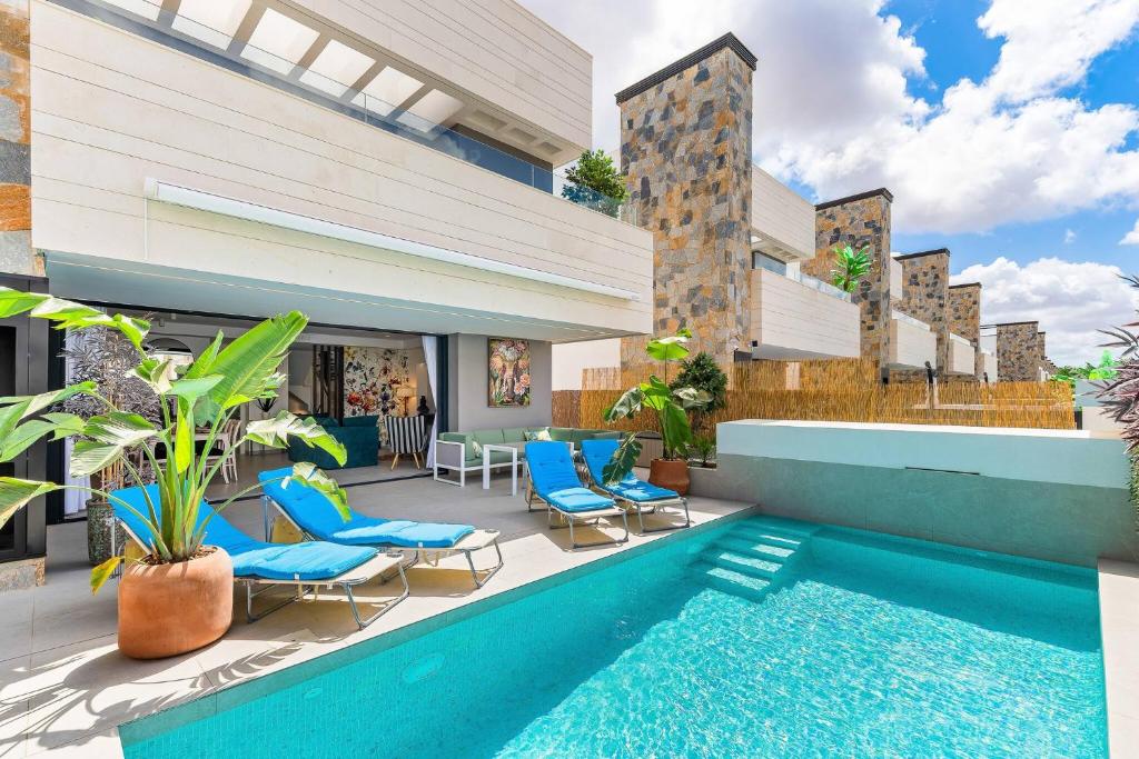 a patio with a swimming pool and blue chairs at Villa de lujo con jacuzzi, cine, billar y futbolín in Murcia