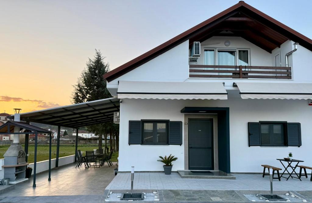a white house with a porch and a patio at Eunoia Homestay & BnB - Loutra Pozar, Aridaia in Aridaia