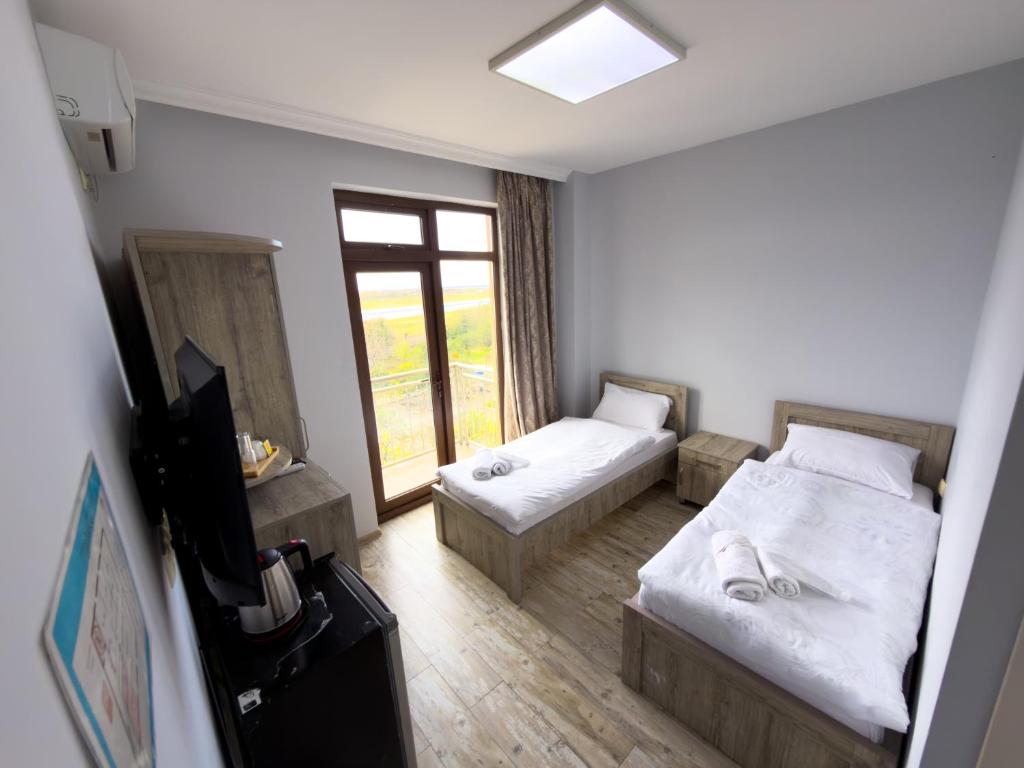 a hotel room with two beds and a window at Three Lion Hotel in Batumi